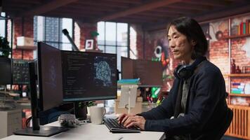 AI startup senior programmer overseeing deep learning application, thinking how to improve software. Asian artificial intelligence tech venture engineer using PC to fix code bugs, camera A video