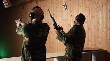 Team of army soldiers practicing with firearms in shooting range to increase firing accuracy. Military units in shooting gallery using pistols and rifles to engage targets at extended range, camera A video