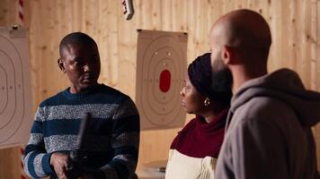 Shooting range safety officer demonstrating how to safely reload semiautomatic weapon to customers, ensuring they follow rules. Firing range employee teaching proper assault rifle handling, camera B video