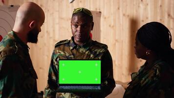 Team of military units at shooting range watching on isolated screen laptop to learn necessary combat skills. Army soldiers looking at instructions on mockup notebook during training, camera B video