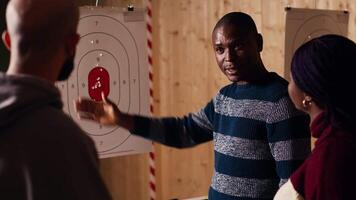 Shooting range safety officer explaining bullseye scoring system to group of mates. African american firing range expert teaching bullseye points system and discussing industry regulations video