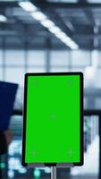 Vertical Isolated screen mockup tablet in front of technicians in blurry background working in server farm, analyzing data. Close up of chroma key tablet next to coworkers examining data center, camera B video
