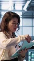 Vertical Data center team reviewing paperwork files in high tech server room, analyzing critical system reports and security protocols. Server room admins looking over financial documents, camera A video