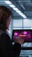 Vertical Data center engineers struggling to contain virus infestation, working on securing servers. Team of server farm employees detecting hacker attacks on tablet, fighting back, camera A video
