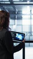 Vertical Data center technicians deploying AI driven management tools using tablet. Server farm coworkers inspecting server clusters, updating network topologies using artificial intelligence, camera B video