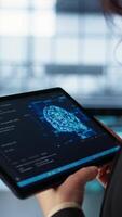 Vertical Data center technician using artificial intelligence on tablet to prevent vulnerabilities. Employee using device to review firewall rules, enforcing AI cybersecurity protocols, camera B close up video