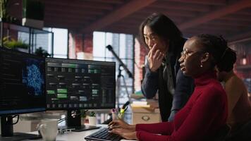Cheerful supervisor in artificial intelligence startup enjoying laughter with worker coding applications. Happy team leader joking with employee doing code testing in relaxed workspace, camera A video