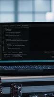 Vertical Laptop used by data center system administrators using artificial intelligence tech, handheld camera shot. AI programming language on notebook used by server farm employees, camera A close up video