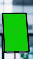 Vertical Isolated screen mockup tablet in front of technicians in blurry background working in server farm, analyzing data. Close up of chroma key tablet next to coworkers examining data center, camera A video