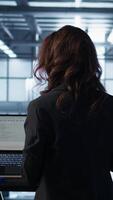 Vertical Technician in data center using AI tech on tablet to adjust power management settings. Engineer in server room optimizes resource utilization using artificial intelligence, camera B video