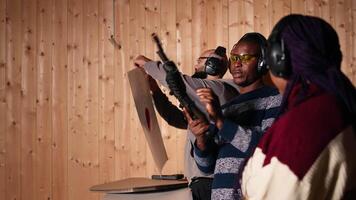 Group of friends in firing range shooting targets, wearing earmuffs to protect hearing. People reloading weapons, using safety gear to prevent damage from gunshots, camera A video
