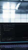 Vertical Laptop used by data center system administrators using artificial intelligence tech, handheld camera shot. AI programming language on notebook used by server farm employees, camera B close up video