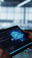 Vertical Programmer in data center using AI tech on tablet, testing equipment failover scenarios. Server farm IT specialist uses artificial intelligence on device, ensuring data accessibility, camera B closeup video