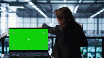 Mockup laptop in front of software developers walking in data center, reviewing equipment diagnostics. Close up of isolated screen notebook next to teamworking IT professionals in server farm video