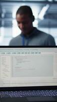 vertical linhas do código em computador portátil exibição usava de trabalho em equipe dados Centro colegas para corre segurança patches. programação língua em caderno usava de servidor quarto isto experts digitalização engrenagem, Câmera b fechar acima video