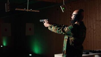 Portrait of happy man training in shooting range, learning pistol holding etiquette, engaging targets at extended range. Joyous army soldier firing lethal fire weapon, camera A video