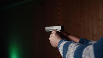 Shooting gallery client using handgun to hit paper targets with ammo. Close up shot of person wearing safety gear at indoor firing range facility shooting bullseyes, enjoying using weapons, camera A video