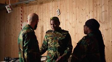Army commander talking with recruits in shooting gallery, teaching them about weapons handling at close quarters. Military officer instructing soldiers, building combat habits, camera A video