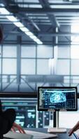 Vertical Data center team reviewing paperwork in server room, analyzing system reports using AI on tablet. Artificial intelligence server room admins looking over financial documents, camera B video