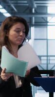 Vertical Data center management executives reading paperwork files, reviewing system diagnostics. Server farm colleagues looking over maintenance schedules documents and cybersecurity protocols, camera A video
