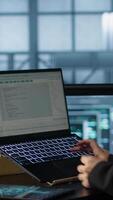 Vertical Technician using laptop in data center, finetuning network protocols, holding coffee cup. Woman in server room coding on notebook, enforcing advanced security measures, camera A video