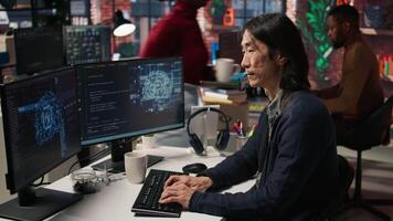CTO manager in artificial intelligence focused startup drinking coffee, listening music and debugging applications. Asian technician putting headphones on, doing code testing, camera A video