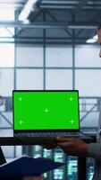 Vertical Engineering team in data center using green screen laptop, implementing predictive analytics scripts, reviewing equipment health, adjusting system parameters, coordinating maintenance tasks, camera A video