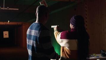 Shooting gallery staff member teaching student how to hold and handle handgun. Firing range expert providing guide to african american woman learning how to achieve proficiency with guns, camera A video