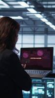 Vertical Cybersecurity expert in data center frantically trying to counter a hacker attack. Server room worker under pressure to secure sensitive information after threat alert received on laptop, camera B video
