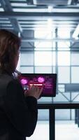 Vertical Data center engineers struggling to contain virus infestation, working on securing servers. Team of server farm employees detecting hacker attacks on tablet, fighting back, camera B video