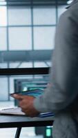 Vertical Admin arriving in data center, using artificial intelligence tech on tablet and laptop. Man in server farm using AI on devices to update storage arrays, improving performance, camera A video