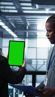 vertical técnicos dentro dados Centro usando verde tela tábua, revendo hardware diagnósticos. isto colegas de trabalho ajustando servidor configurações usando brincar dispositivo, aplicando firmware atualizações, Câmera b video