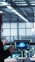 Vertical Team of engineers in data center with tablet integrating AI driven automation tools, doing maintenance. Teamworking colleagues in server room using artificial intelligence, camera B video
