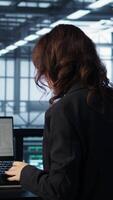 Vertical Programmer using laptop in data center, finetuning network protocols, drinking coffee. Woman in server farm coding on notebook, enjoying beverages, enforcing advanced security measures video