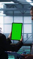 vertical técnicos dentro dados Centro usando verde tela tábua, revendo hardware diagnósticos. isto colegas de trabalho ajustando servidor configurações usando brincar dispositivo, aplicando firmware atualizações, Câmera uma video