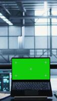 Vertical Coworkers in data center using mockup laptop, integrating green technologies. IT experts in server room using chroma key notebook to implement sustainable energy solutions, camera B close up video