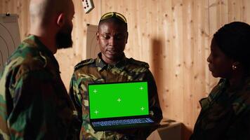 Team of military units at shooting range watching on isolated screen laptop to learn necessary combat skills. Army soldiers looking at instructions on mockup notebook during training, camera A video