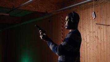 Portrait of smiling man doing training in shooting range, learning proper pistol holding etiquette and having fun. Cheerful gun hobbyist practicing with weapons, wearing protective eyewear, camera A video