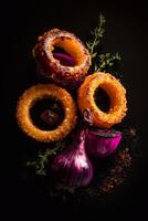 Crunchy onion rings, roasted garlic, and caramelized onion pieces with thyme and salt on a black background. A gourmet food composition with strong contrast and artistic lighting. . photo