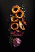 Crispy golden onion rings with roasted garlic, caramelized onion wedges, fresh thyme, and sea salt on a dark background. A gourmet composition with rich textures and deep contrast. . photo