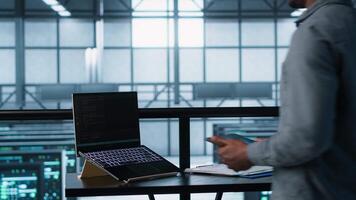 Technician in data center using AI on laptop and tablet, developing disaster recovery plans. Server farm employee using artificial intelligence tech on devices, testing failover scenarios, camera A video