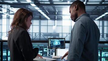 Data center team reviewing paperwork in server room, analyzing system reports using AI on tablet. Artificial intelligence server room admins looking over financial documents, camera B video