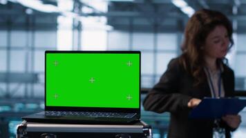 Green screen laptop used by data center admins in blurry background reviewing equipment diagnostics. Chroma key notebook used by coworkers adjusting server room configurations, camera A video