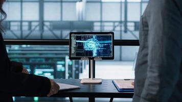 Team of IT professionals looking over data center checkup paperwork, using AI tech on tablet. Colleagues collaborating in server farm, reading documentation, using artificial intelligence, camera A video