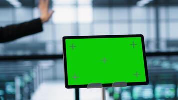 Focus on chroma key device in front of data center technicians analyzing metrics. Close up of isolated screen tablet next to server hub workers ensuring seamless operations, camera A video