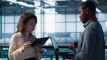 Data scientists in server room using laptop and tablet, executing security patches, verifying firewall configurations. People performing equipment vulnerability scans in data center, camera A video
