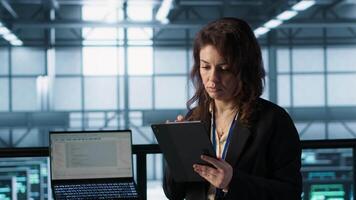 Admin in data center using artificial intelligence tech on tablet to deploy new server architectures. Woman in server room updating storage arrays to maintain stable performance, camera A video