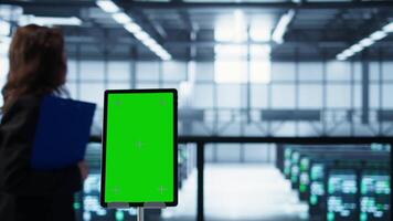 Isolated screen mockup tablet in front of technicians in blurry background working in server farm, analyzing data. Close up of chroma key tablet next to coworkers examining data center, camera B video