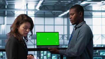 Technicians in data center using green screen mockup laptop to develop disaster recovery plans. IT specialists in server farm testing failover scenarios on chroma key device, protecting data, camera A video
