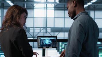 Data center team reviewing paperwork in server room, analyzing system reports using AI on tablet. Artificial intelligence server room admins looking over financial documents, camera A video